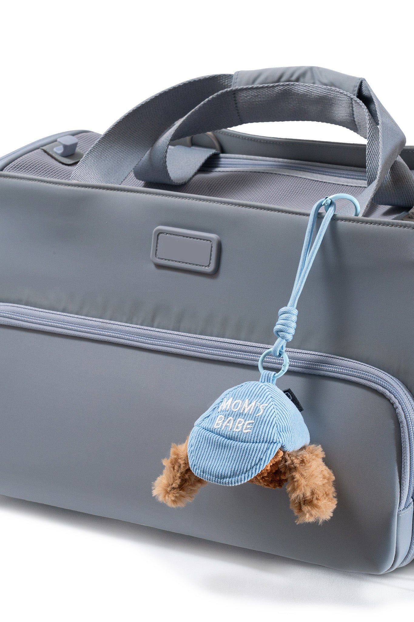 Close-up of the blue Pup Charm secured to a pet carrier with its lightweight cord and clip attachment, a must-have travel essential for dogs.