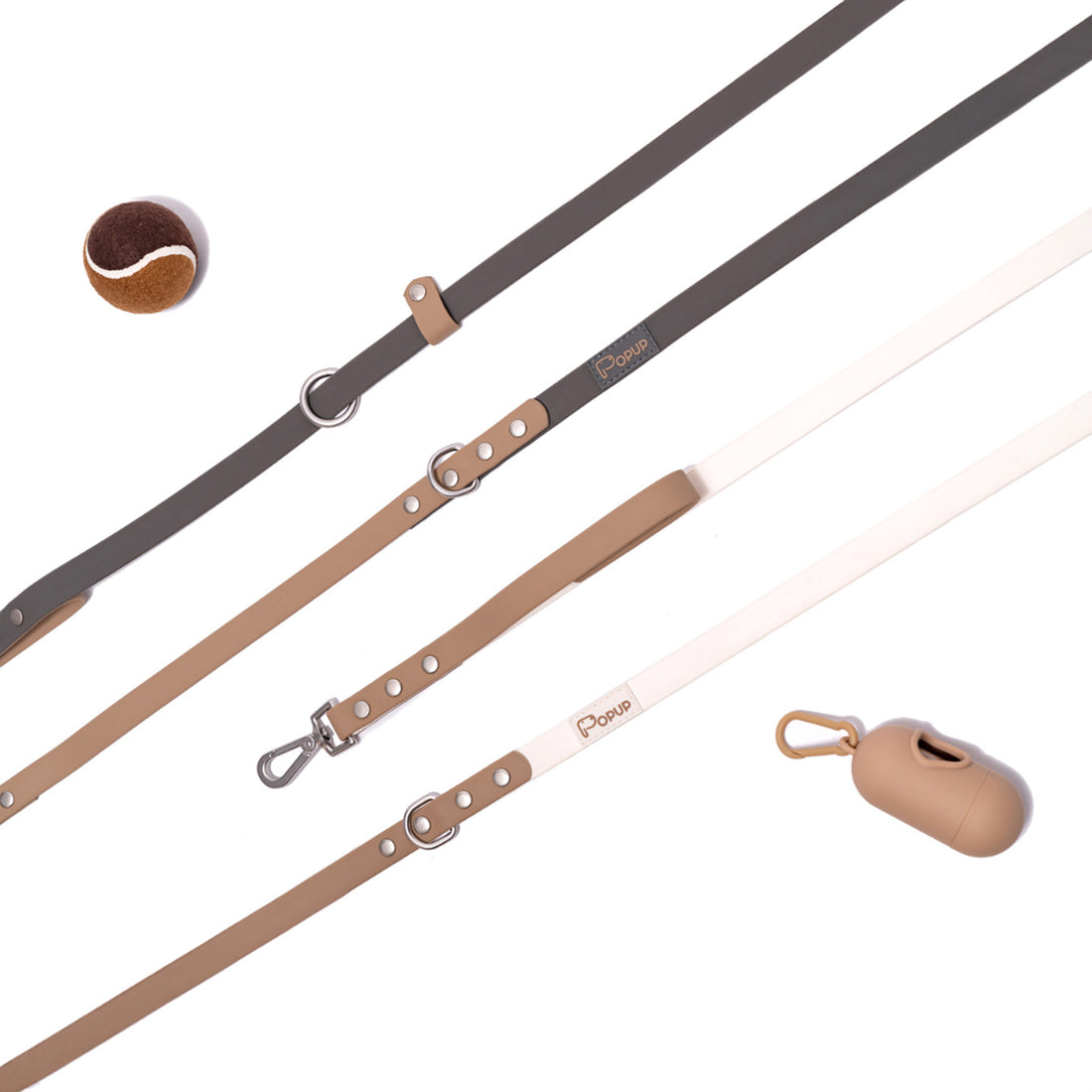 Flat lay of DUO leashes with matching waste bag holder and ball in neutral tones