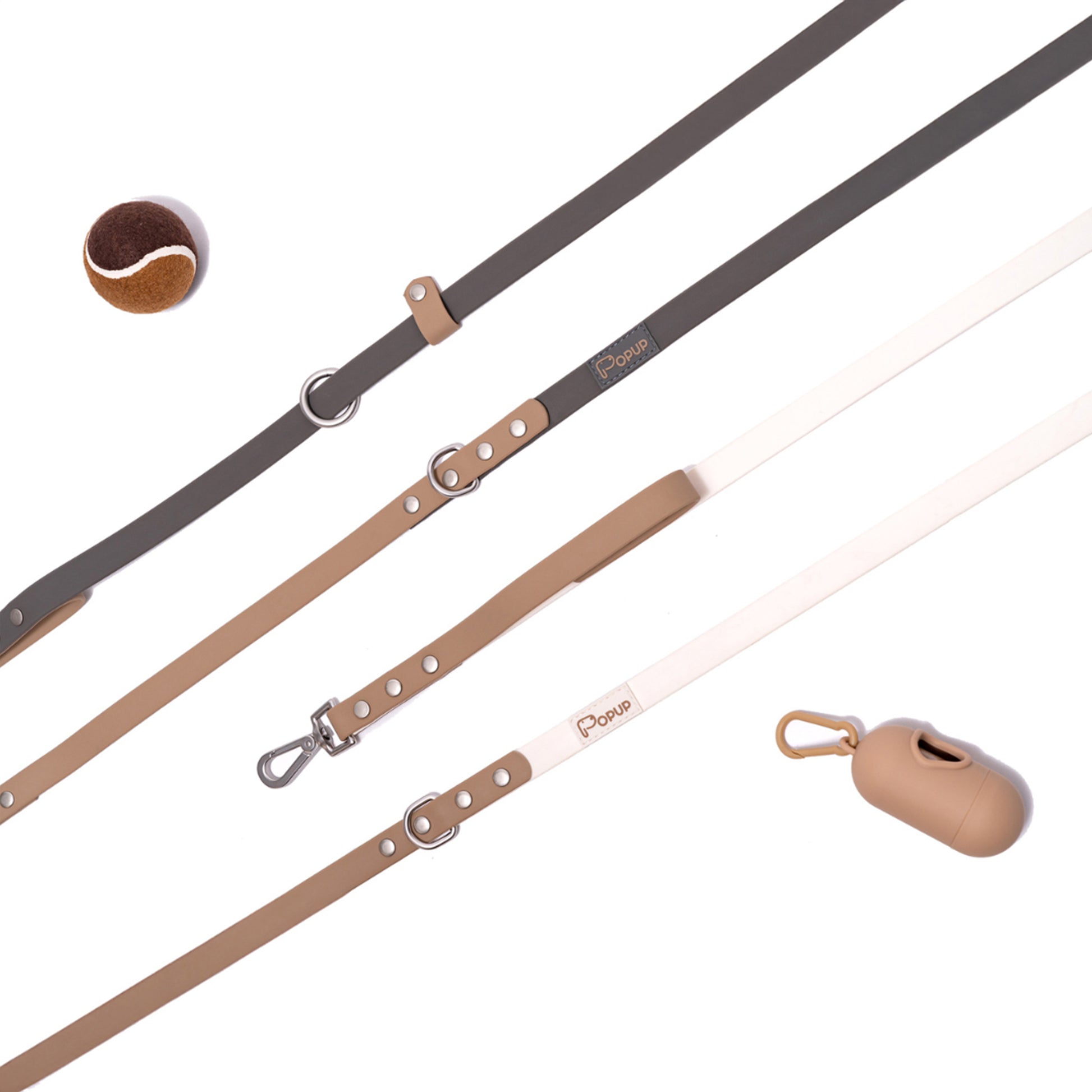 Flat lay of DUO leashes with matching waste bag holder and ball in neutral tones