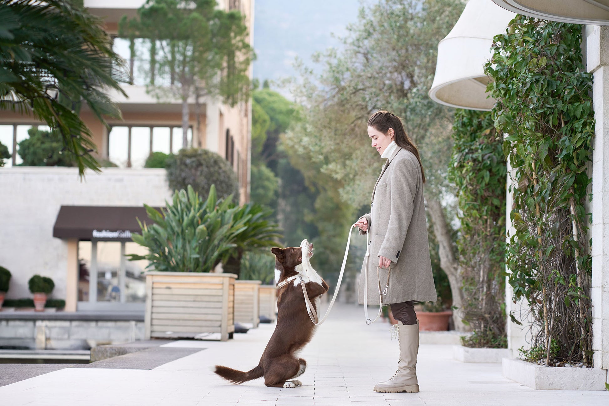 Woman training dog on leash in outdoor walkway using DUO Premium for structured control