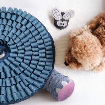 Blue dog snuffle mat with puzzle plush toy beside small curly-haired puppy